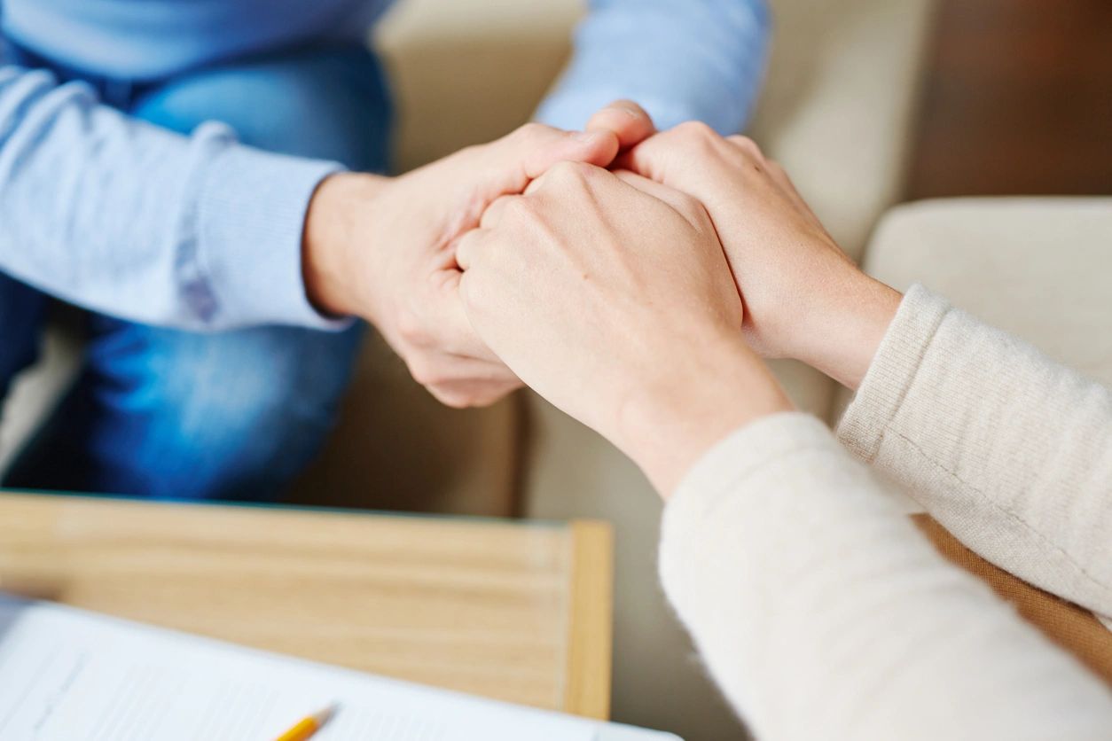 Two people holding hands while sitting at a table.